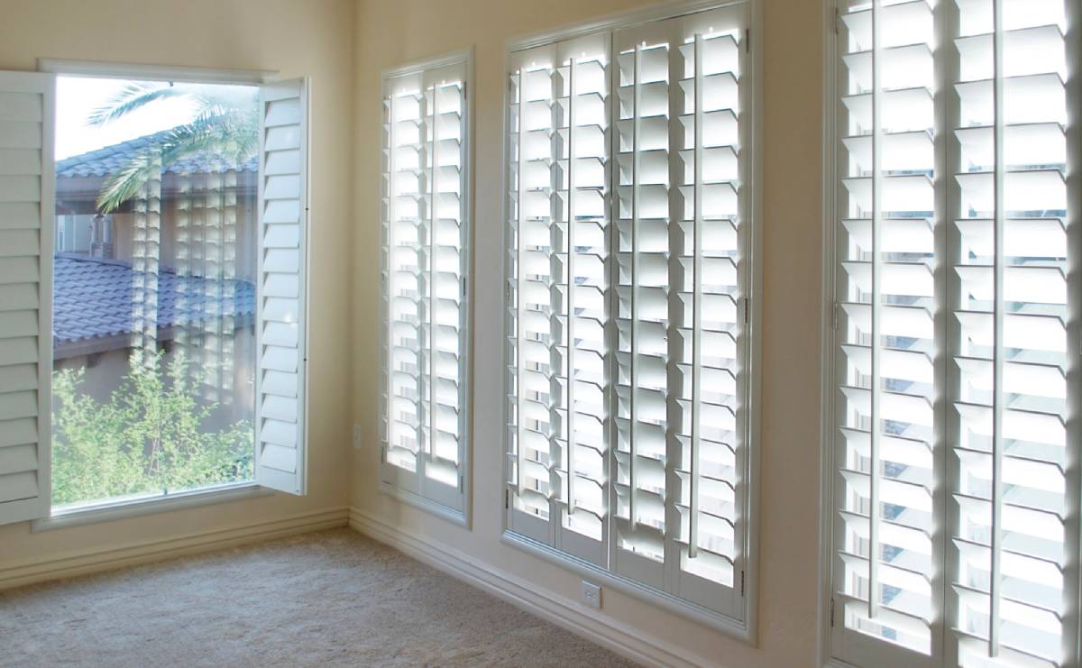 an empty room with a window and shutters